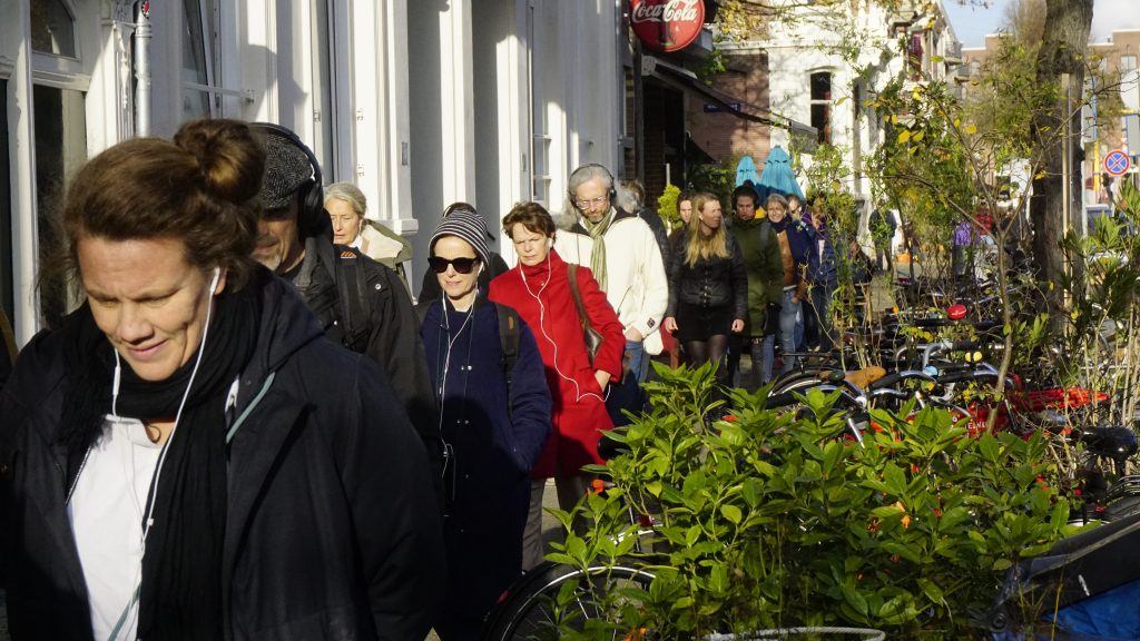 Deelnemers aan De Tegentijd lopen door Amsterdam